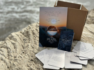 Diving for pearls workbook and question cards on a rocky surface with water in the background