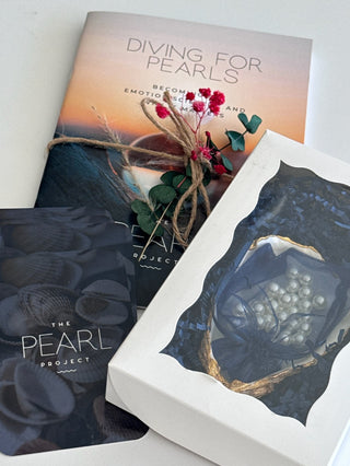 Flatlay of diving for pearls mental health kit, including diving for pearls workbook, question cards, and box with oyster shell and pearls inside