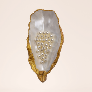 Oyster half-shell painted gold with pearls inside.